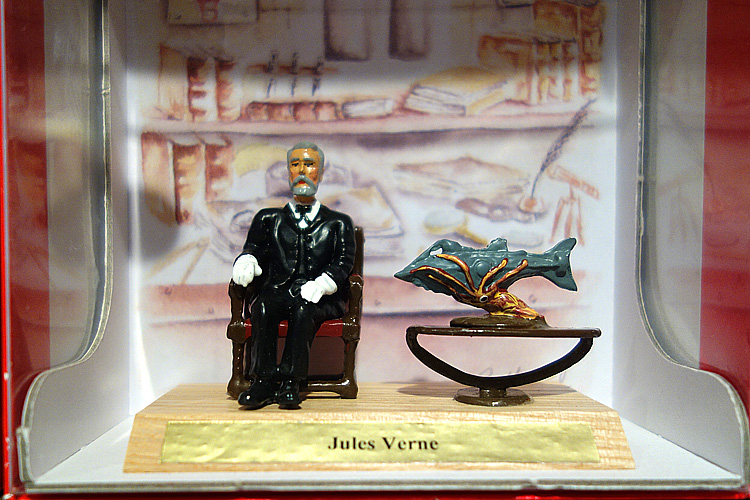 Une très belle figurine de plomb du Capitaine Némo de Jules Verne assis sur un fauteuil.
On peut voir à sa gauche une table avec le Nautilus happé par la pieuvre géante © Photogriffon