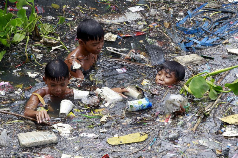 BEST POLLUTION IN THE WORLD - Les enfants jouent dans l'eau polluée aux Phlippines en se marrant, l'inconscience à l'état pur © Photo sous Copyright