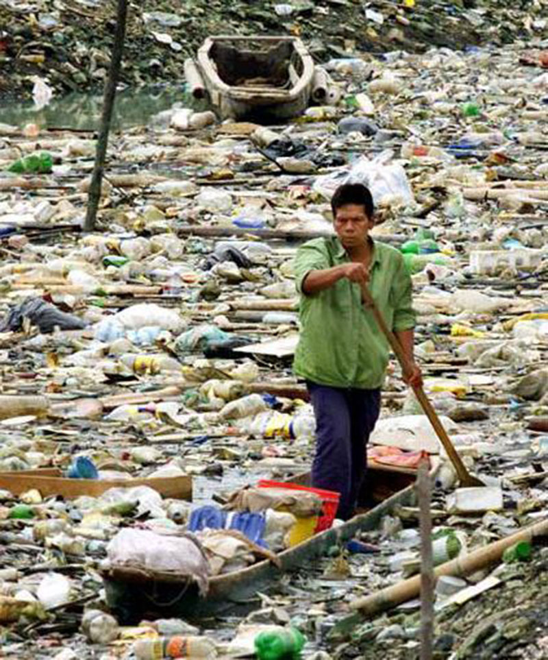 BEST POLLUTION IN THE WORLD -Cet homme essaye de se frayer un chemin parmi les poubelles qui flottent, scène apocalyptique ! © Photo sous Copyright 
