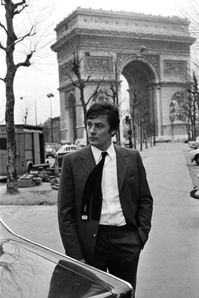 Alain Delon devant l'Arc de Triomphe, on distingue un Type H à gauche de la photo pour