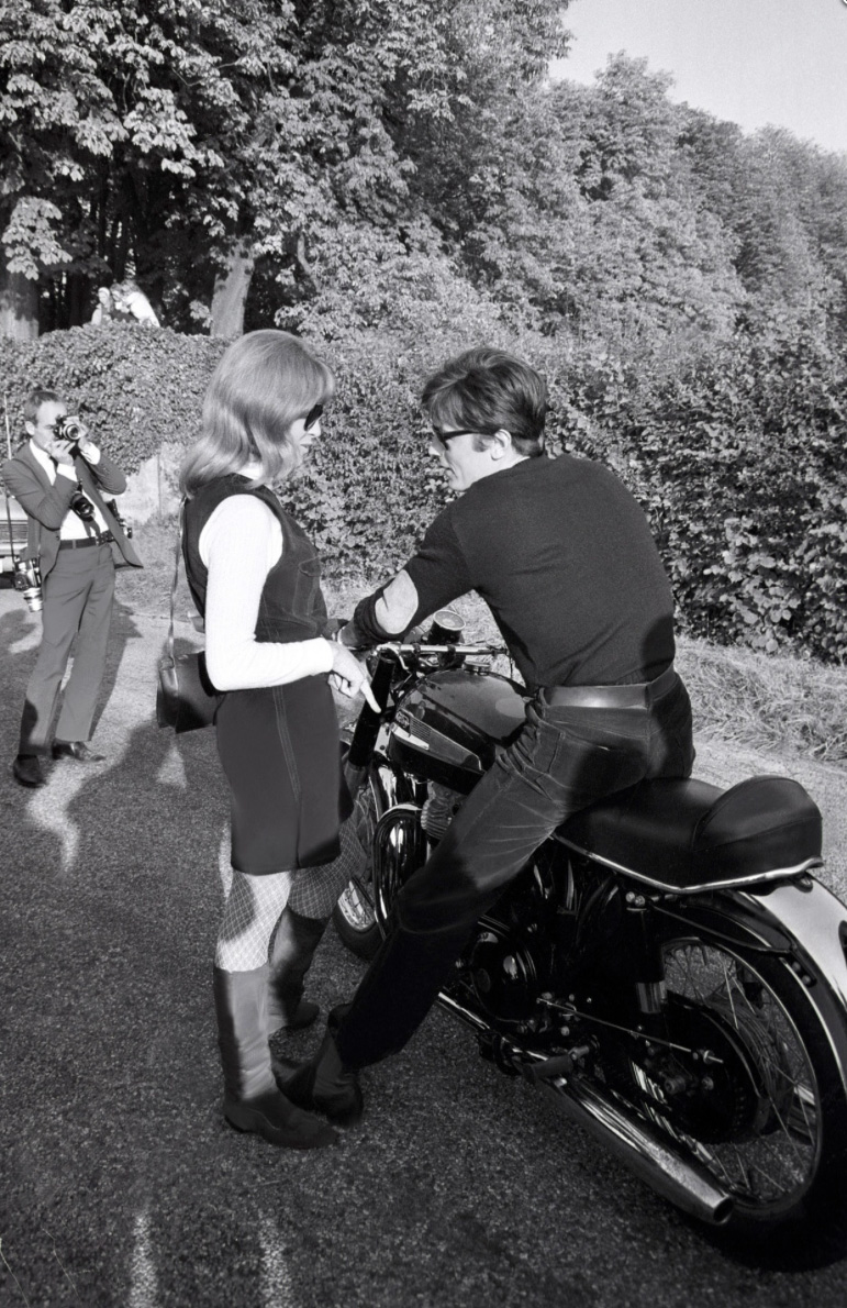 Alain Delon sur sa moto avec Nathalie Delon à ses côtés en pleine discussion - 1968 © Photo sous Copyright